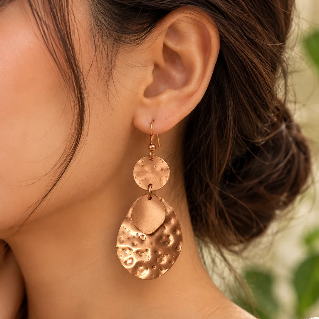 Hammered copper drop earrings for women worn with a stylish outfit